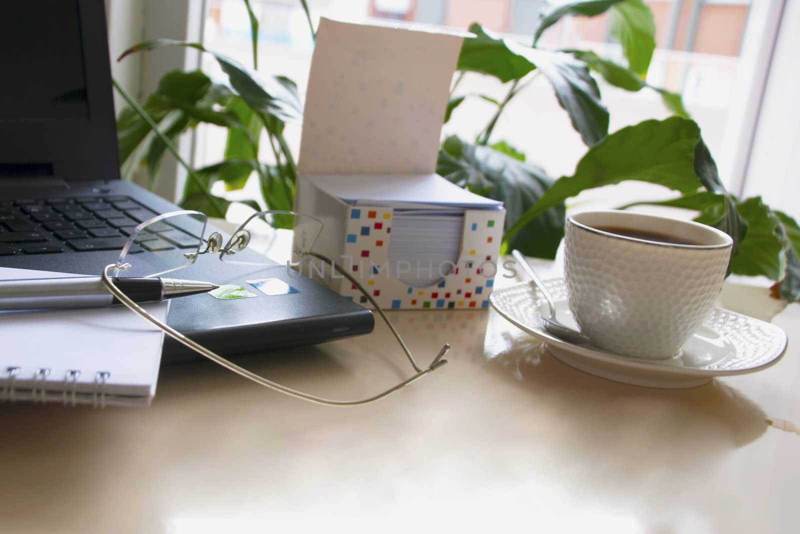 Work desk with laptop computer and hot coffee cup with defocused background.