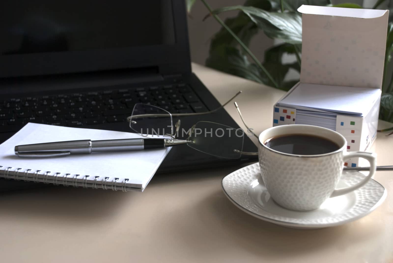 Blank notepad over laptop and coffee cup. Work desk with laptop computer and hot coffee cup with defocused background