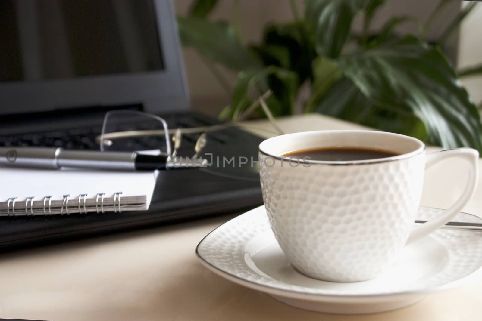 Blank notepad over laptop and coffee cup. Work desk with laptop computer and hot coffee cup with defocused background