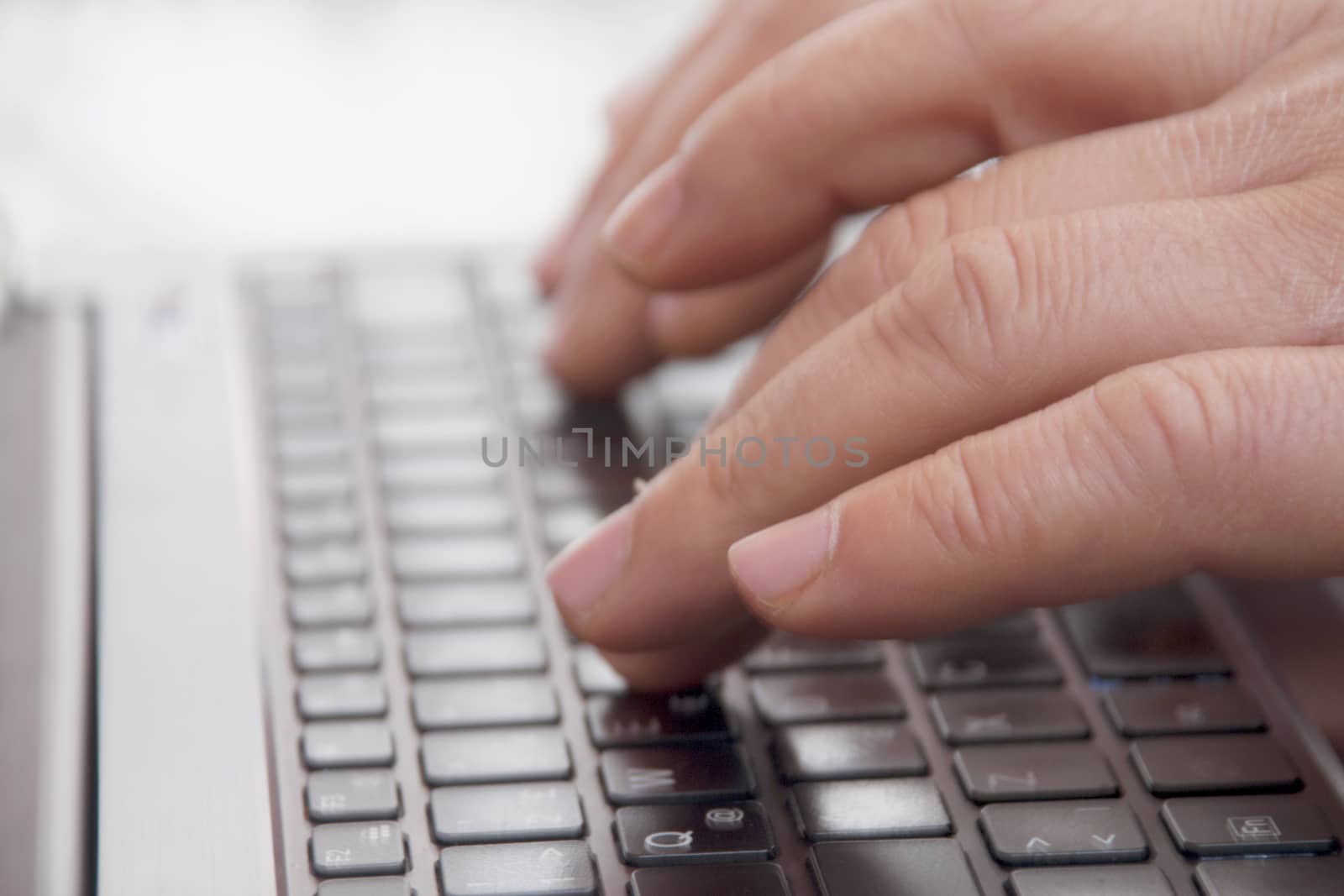 Close-up view of the hands on the keyboard while working with a businessman laptop.