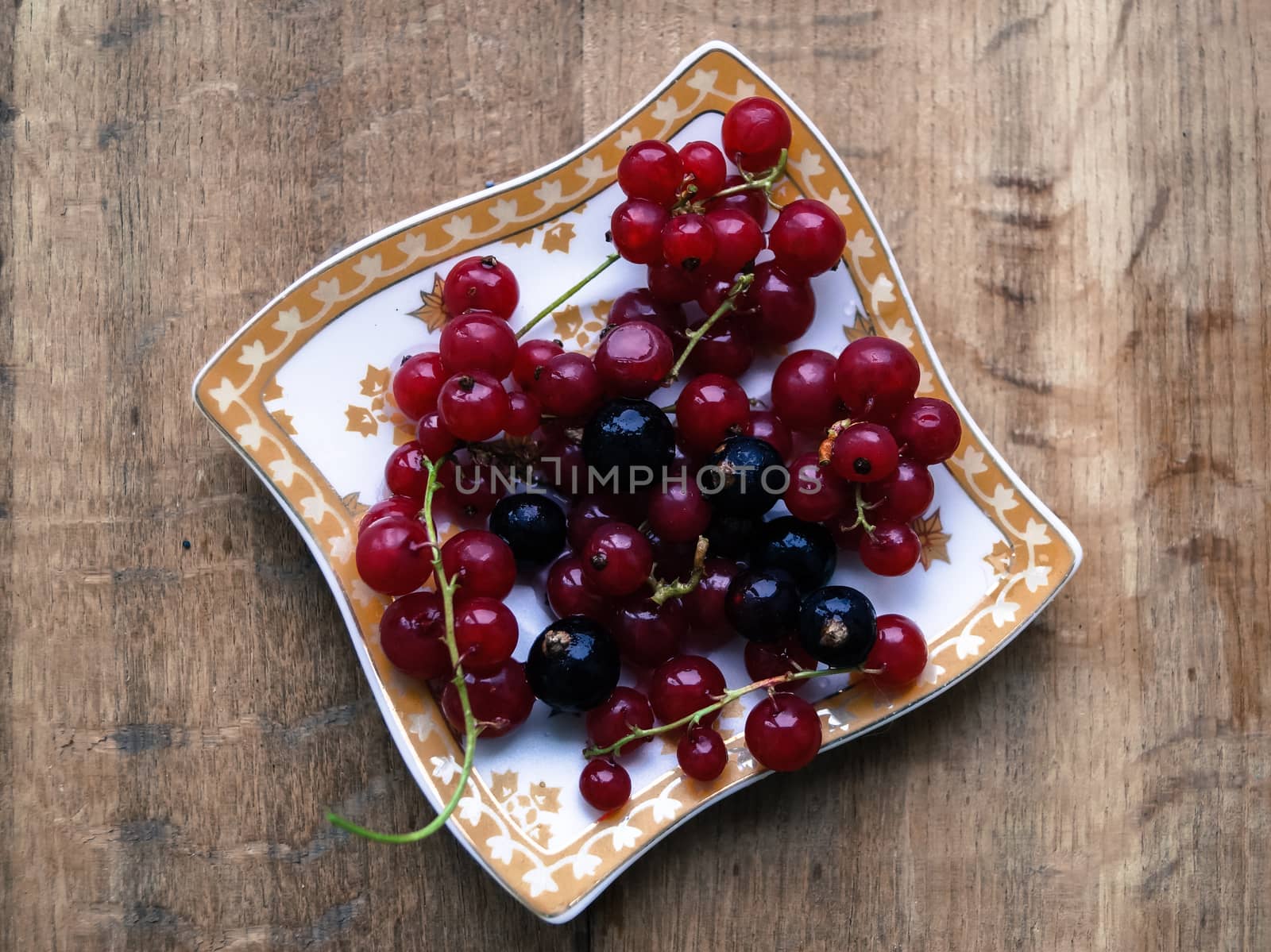 currant berries on a plate on a wooden table by Oleczka11