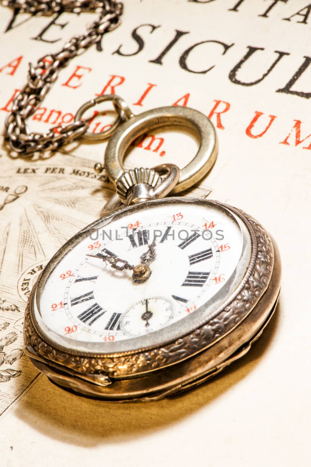 antique pocket watch on ancient Bible into Latin