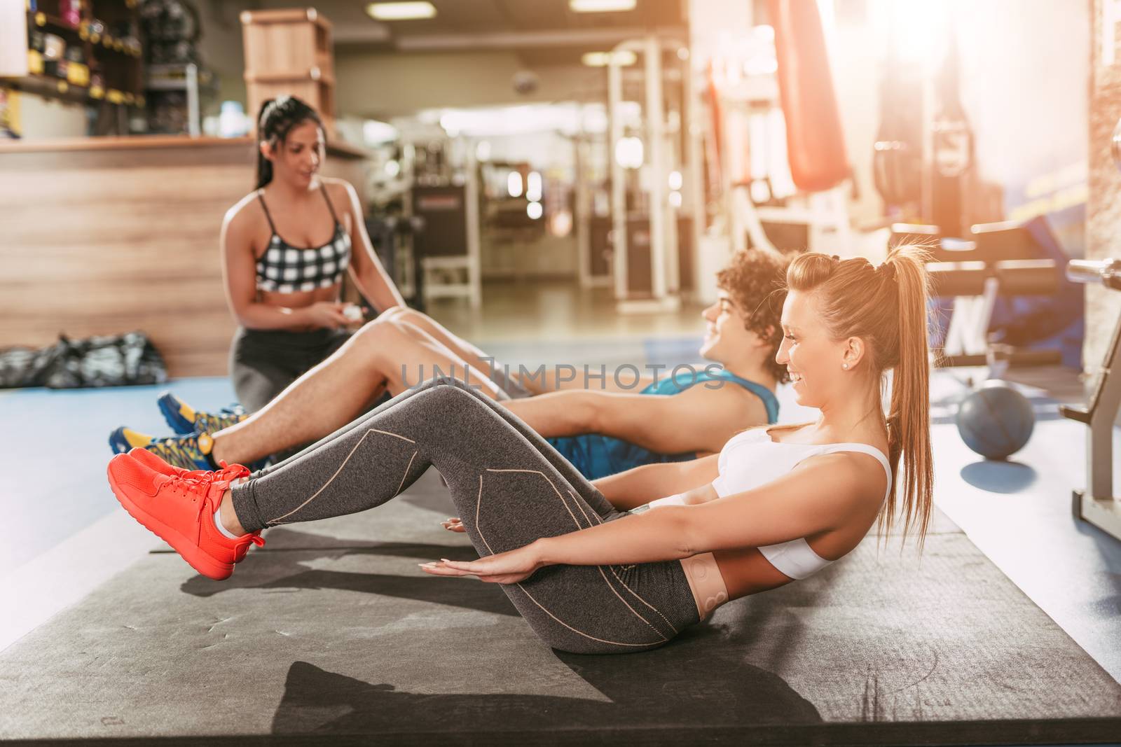 Beautiful happiness couple exercising at the gym with a female personal trainer.