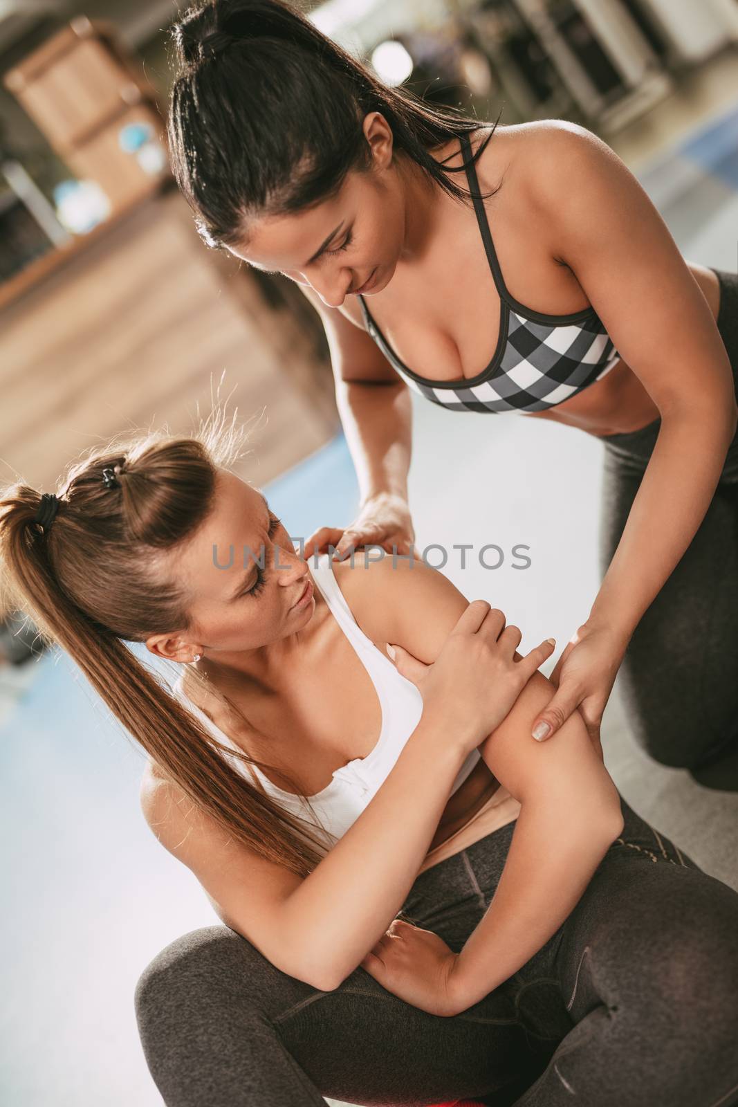 Female fitness instructor assisting young woman who had injured herself at the gym.