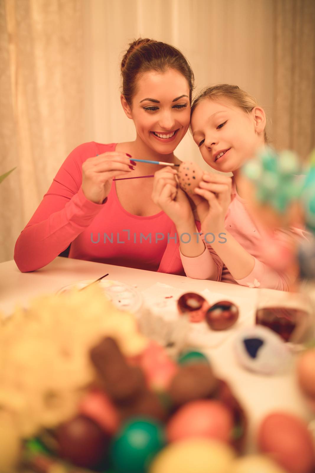 Beautiful happiness mother and daughter painting Easter egg at home.