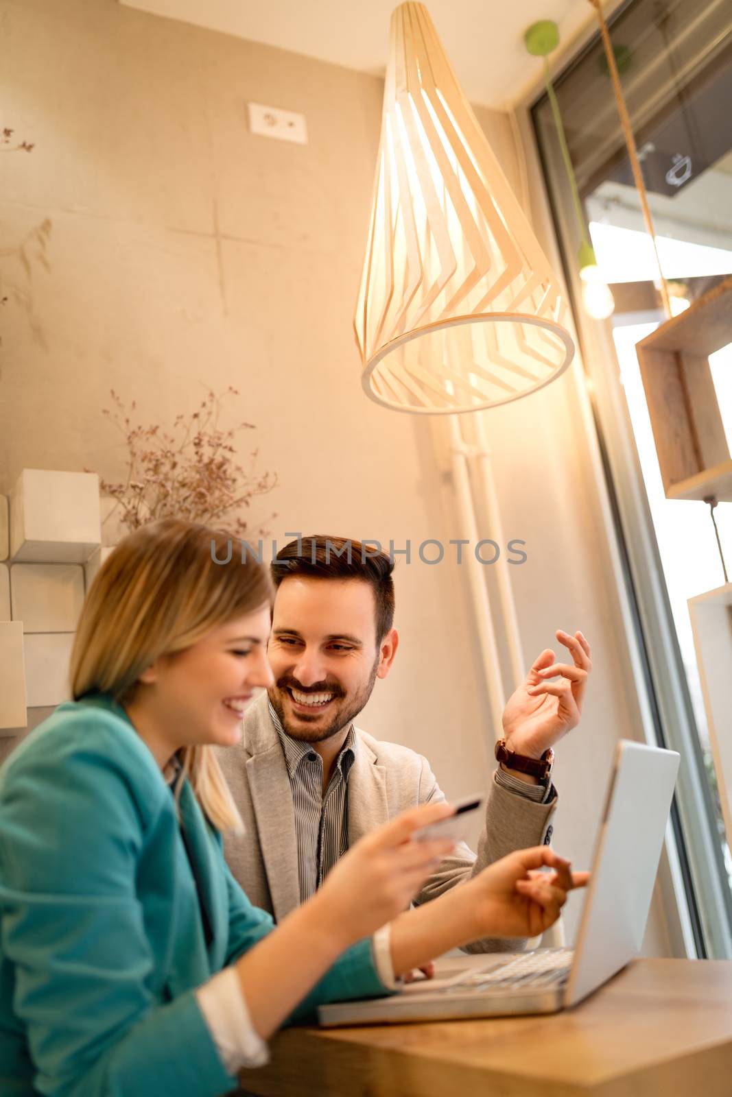 Young beautiful smiling couple sitting at cafe and shopping online on laptop.