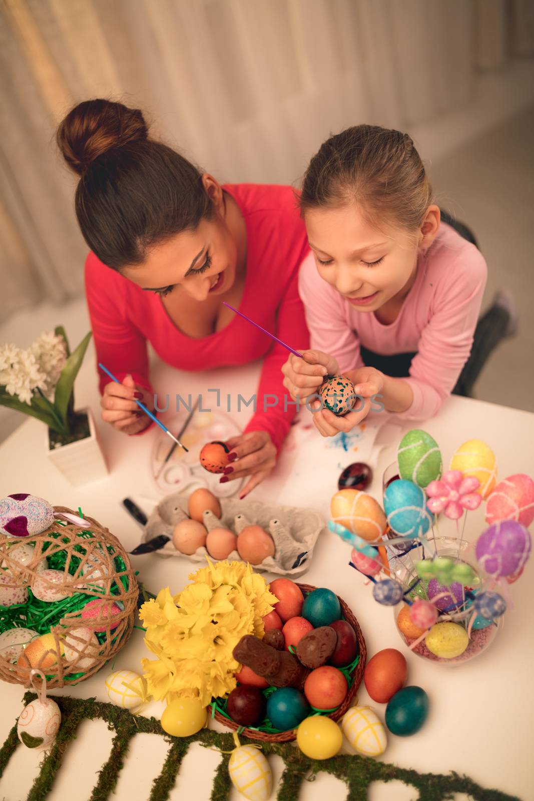 Beautiful happiness mother and daughter painting Easter egg at home.