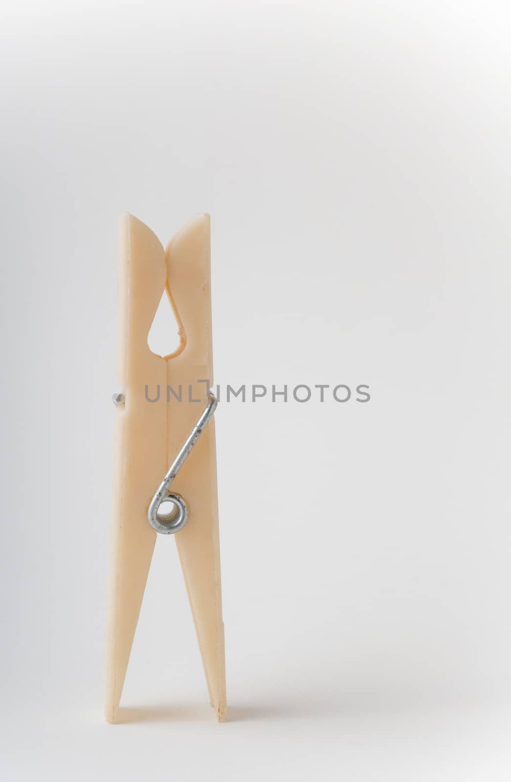 Closeup of isolated plastic clothespin standing on end with isolated white background.