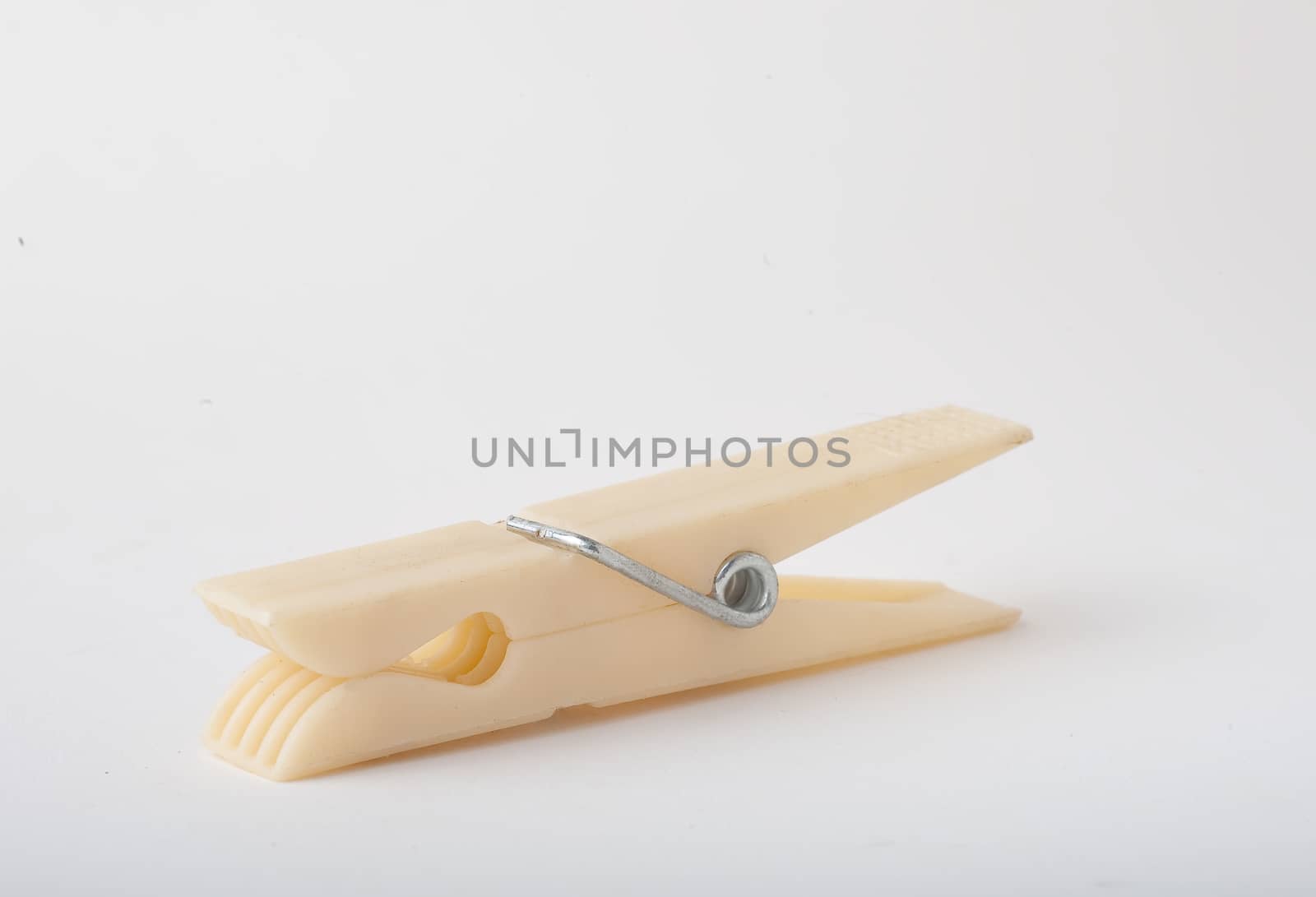 Plastic clothes pin closeup, lying down on side with isolated white background.