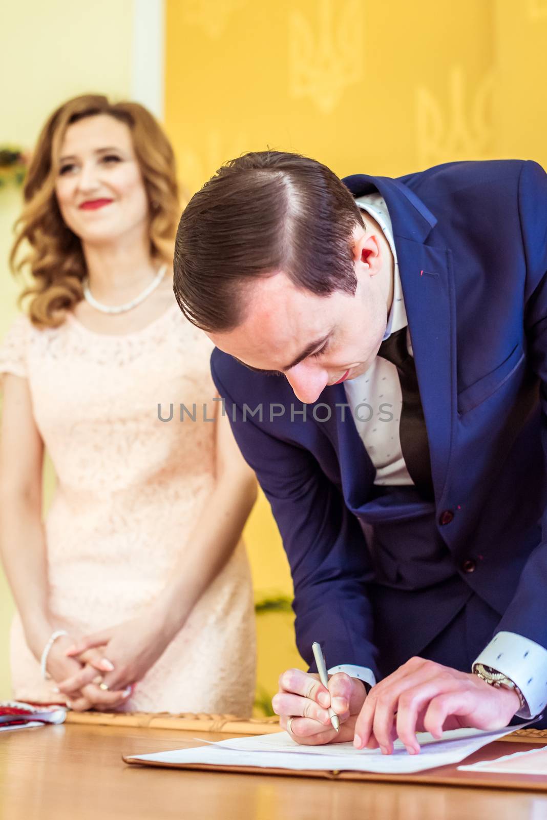 Gorgeous bride and groom signing wedding certificate at the registry office in Lviv, Ukraine