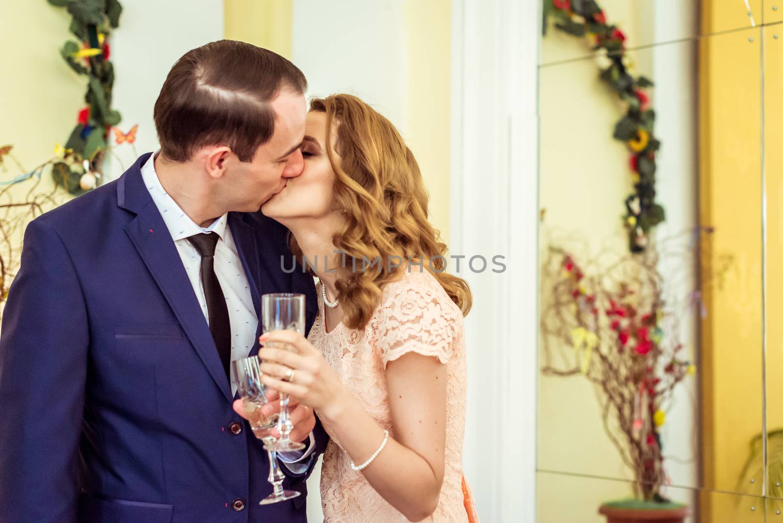 Man and woman kissing and drinking champagne in a registry office during the ceremony in Lviv, Ukraine