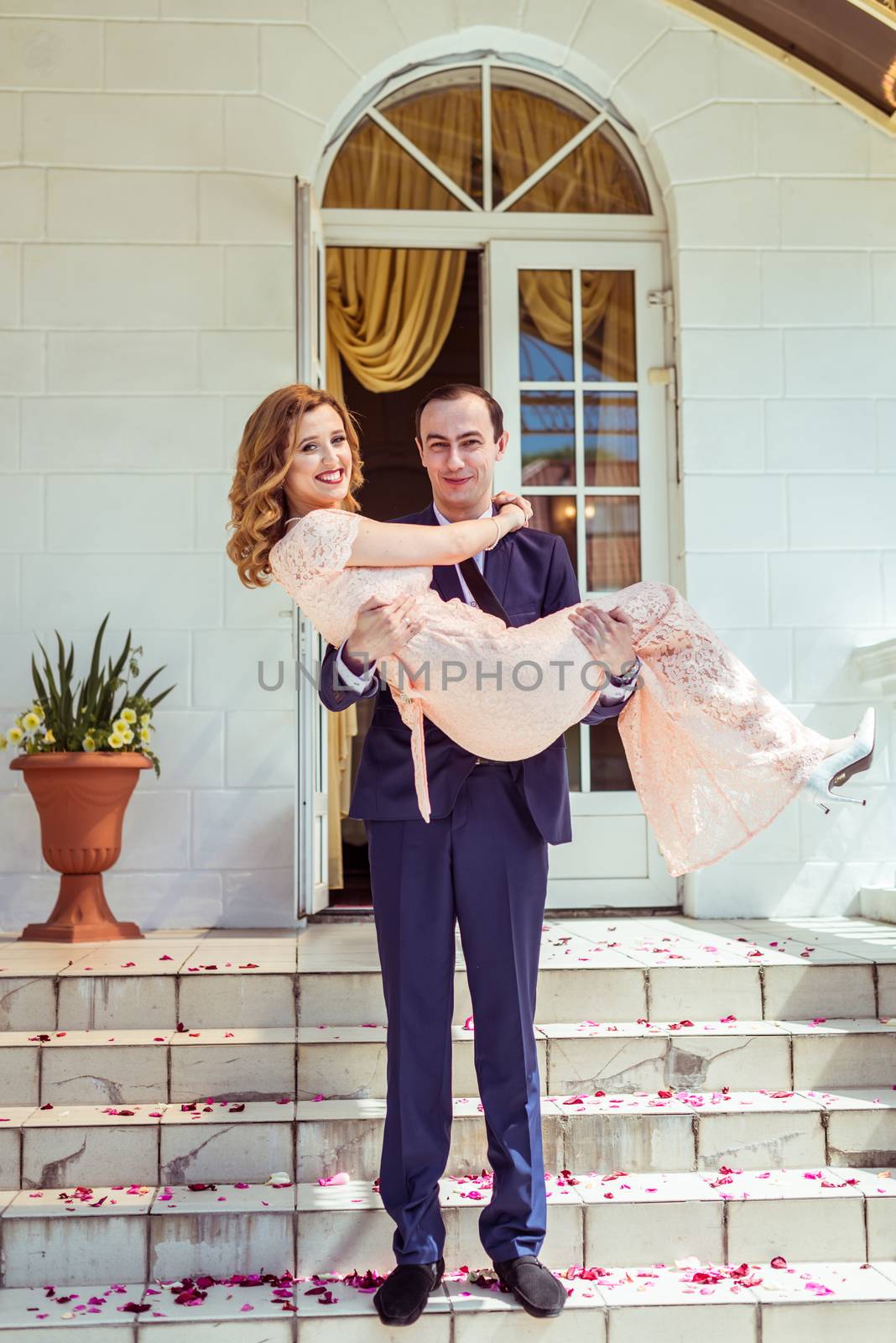 Groom holding bride in his arms after the ceremony at the registry office in Lviv, Ukraine