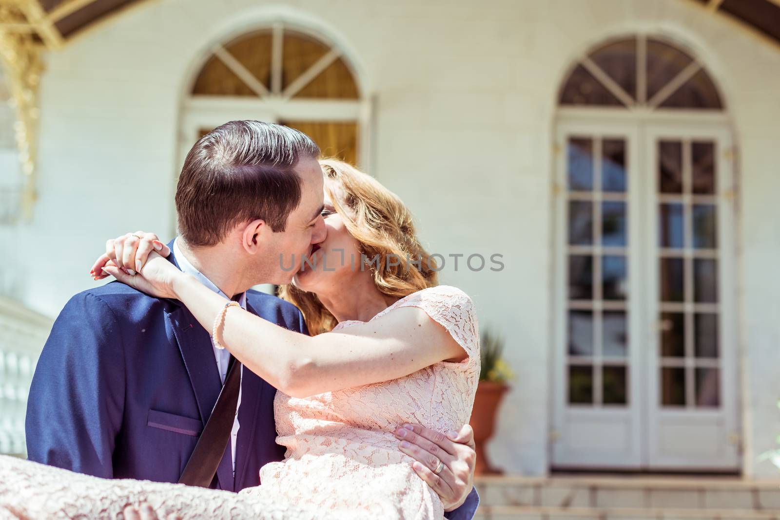 Groom holding bride in his arms and kissing after the ceremony at the registry office in Lviv, Ukraine