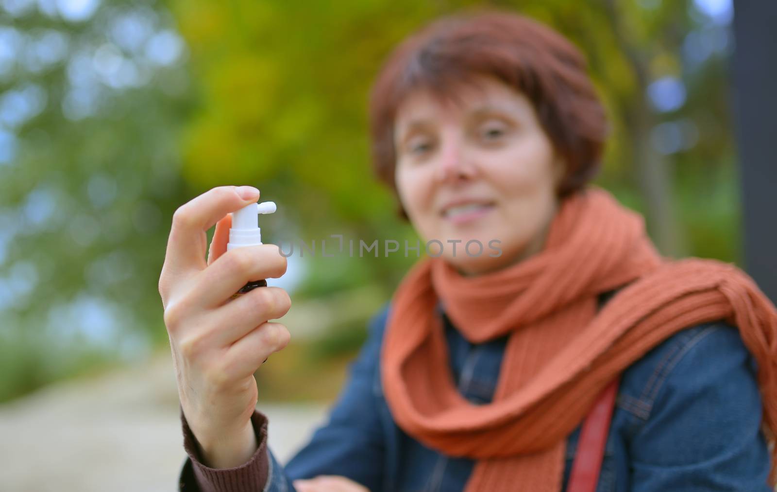 Young woman using throat spray in cold season