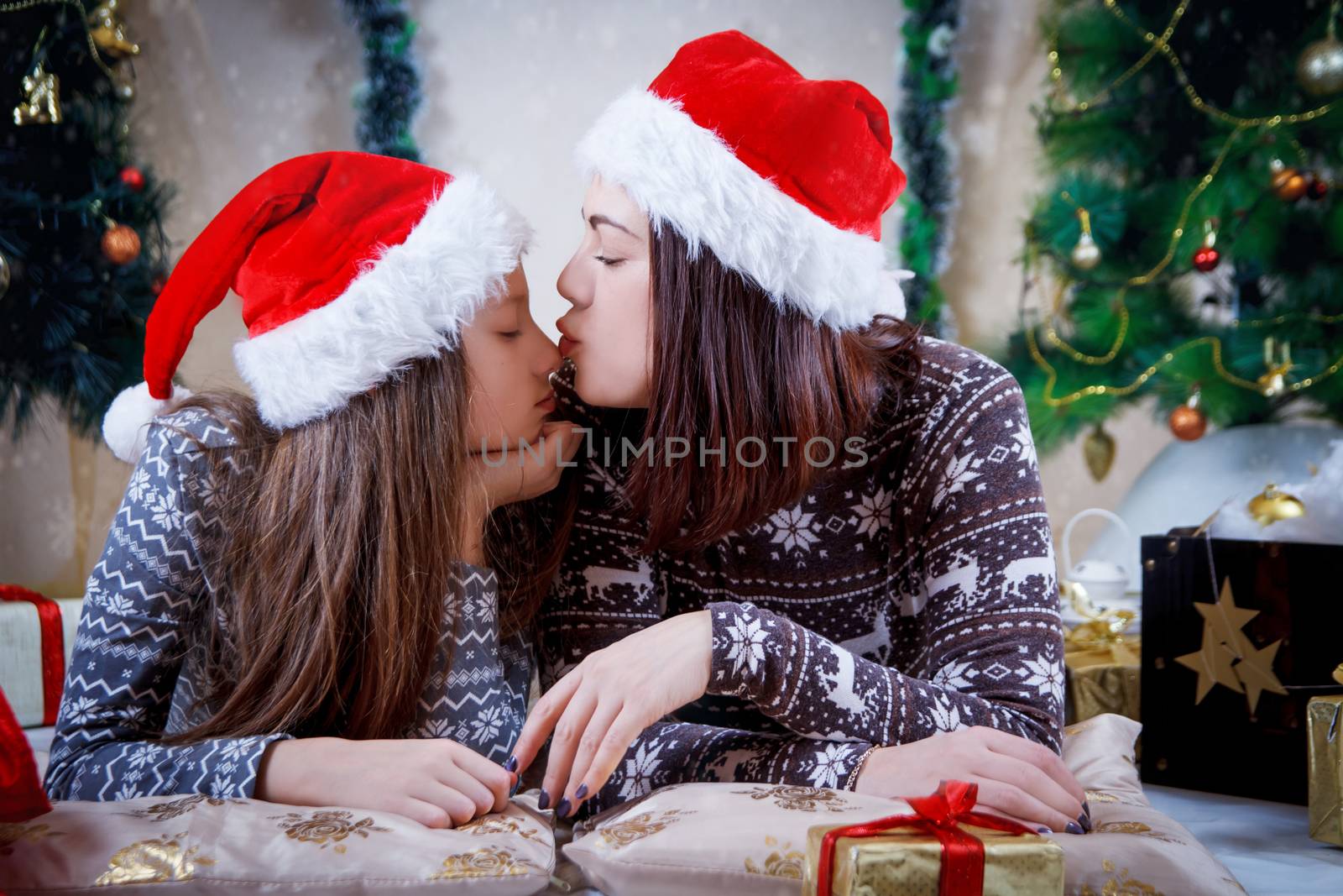 Mother kissing daughter nose under Christmas tree