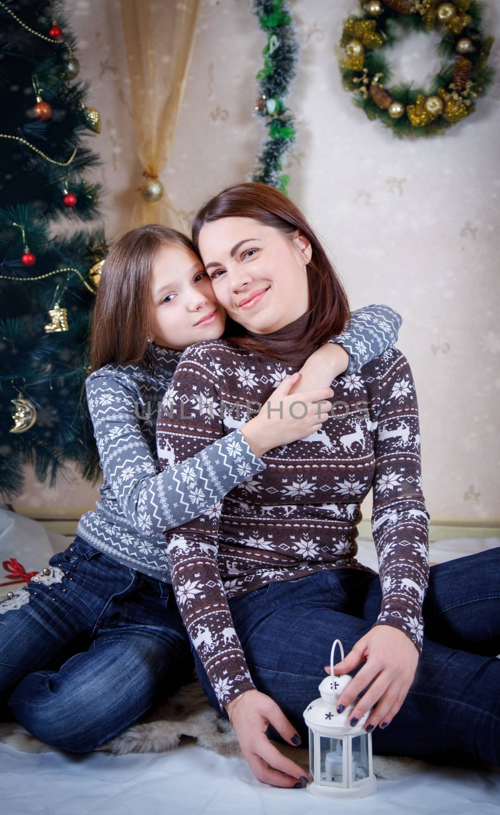 Mother and daughter sitting under Christmas tree