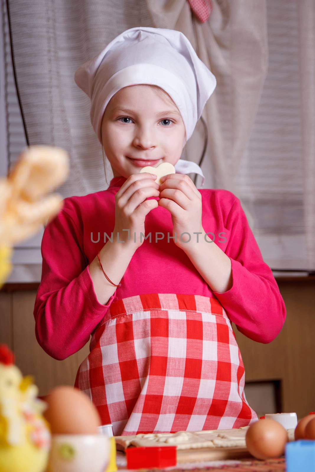 Girl in apron making heart-shaped cookies