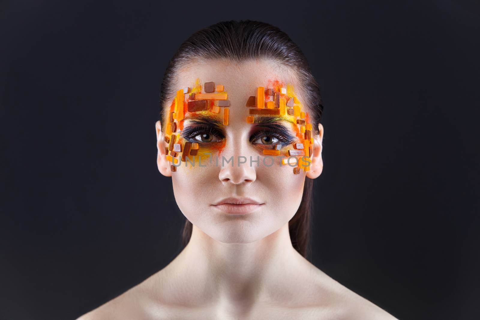 Portrait of a girl with an original make-up. Beauty close-up with orange and red rhinestones on a face of the model