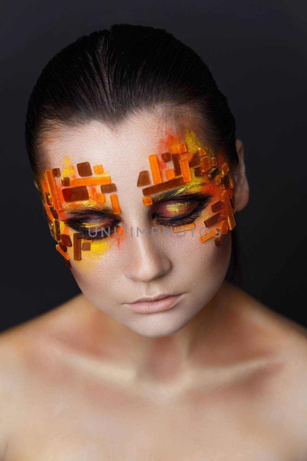 Portrait of a girl with an original make-up. Beauty close-up with orange and red rhinestones on a face of the model