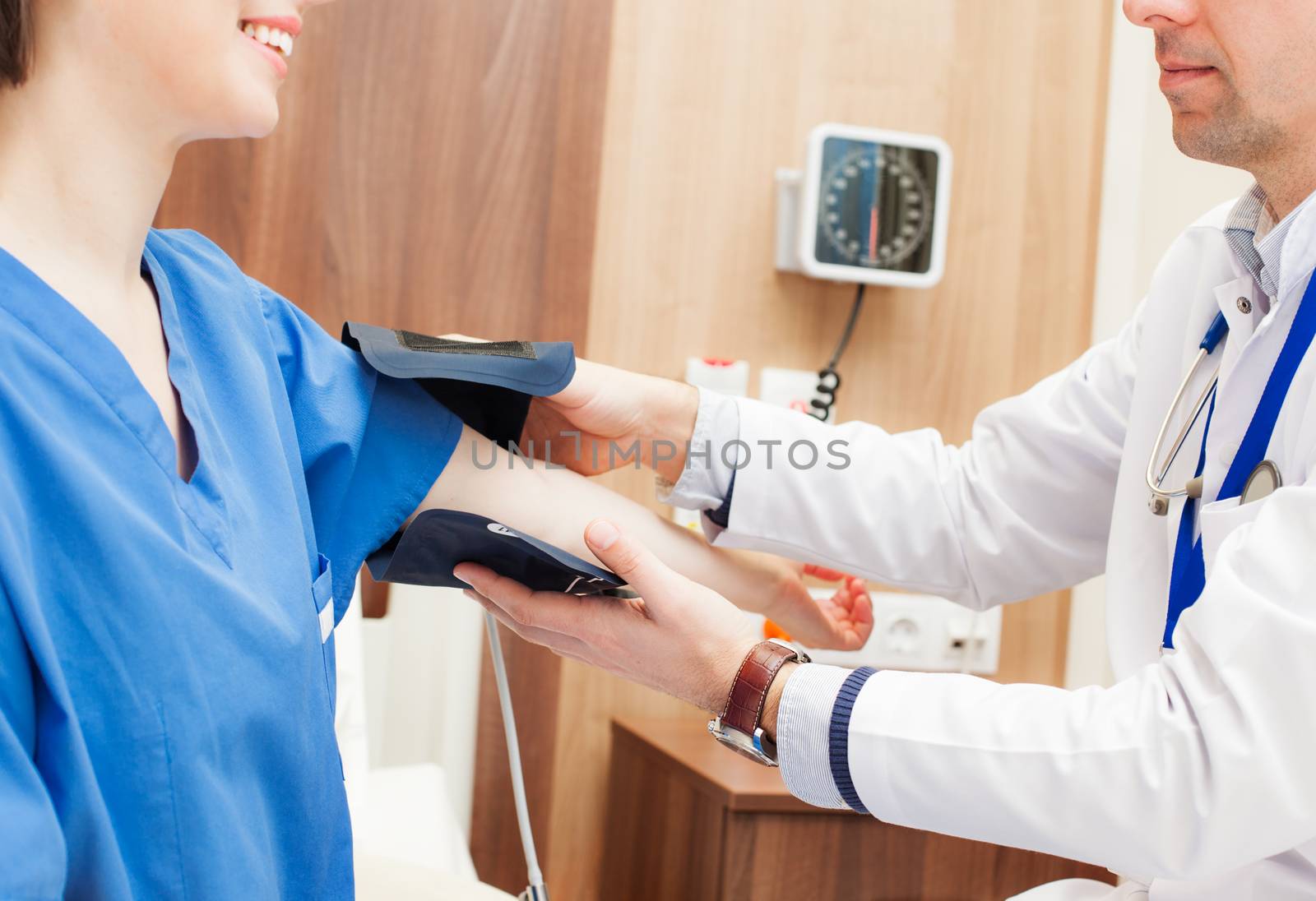 A close-up of a doctor hands measuring blood pressure of a patient in hospital.