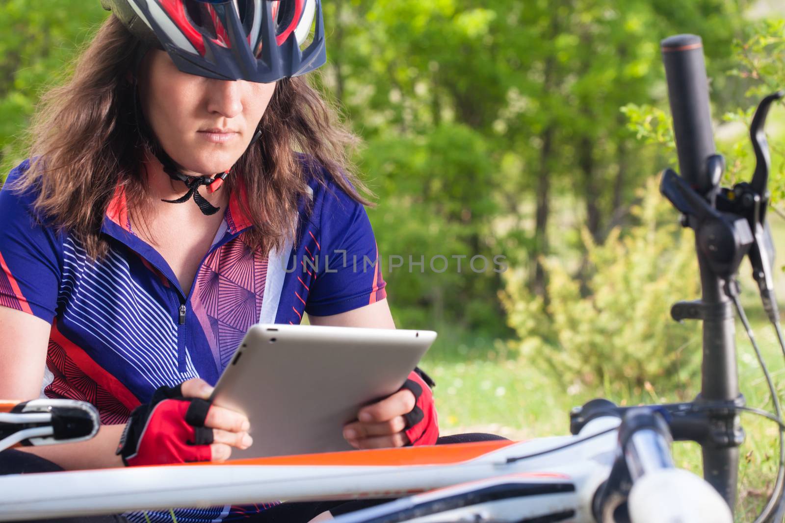 female mountainbiker relaxing and using her tablet in nature
