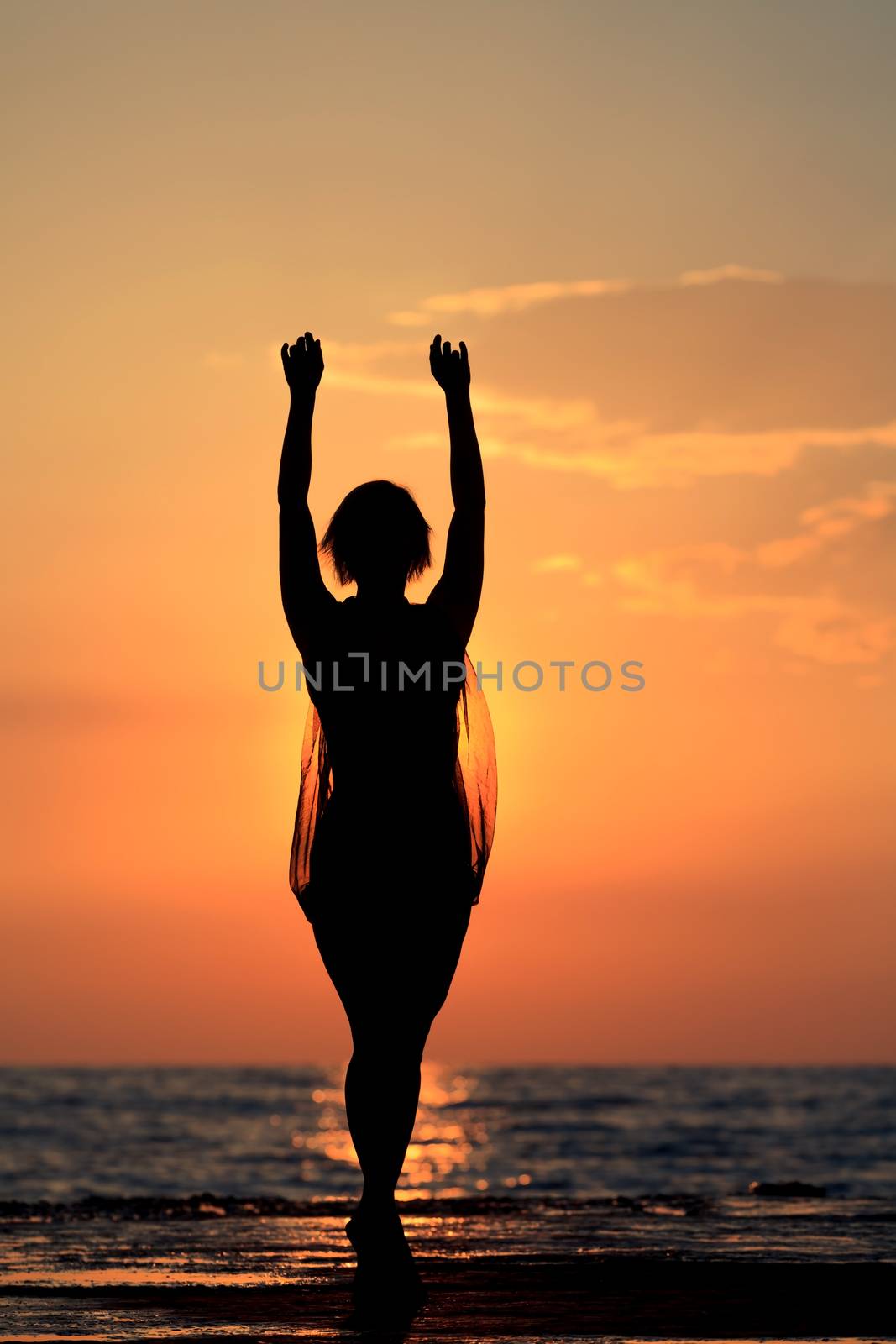 Silhouette of a girl dancing on the background of sea sunset