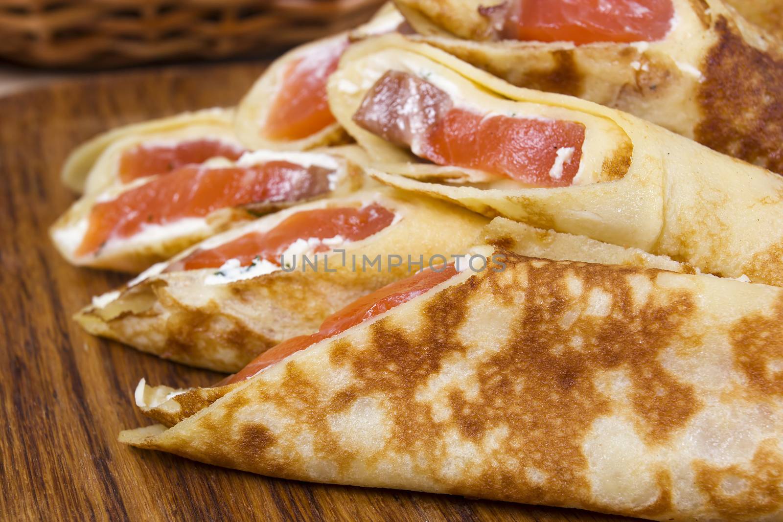 Closeup of pancakes with red fish on a wooden surface