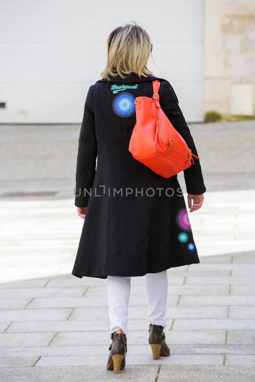 Paris, France - March 27, 2017: Back view of a well dressed blond woman walking on the city streets