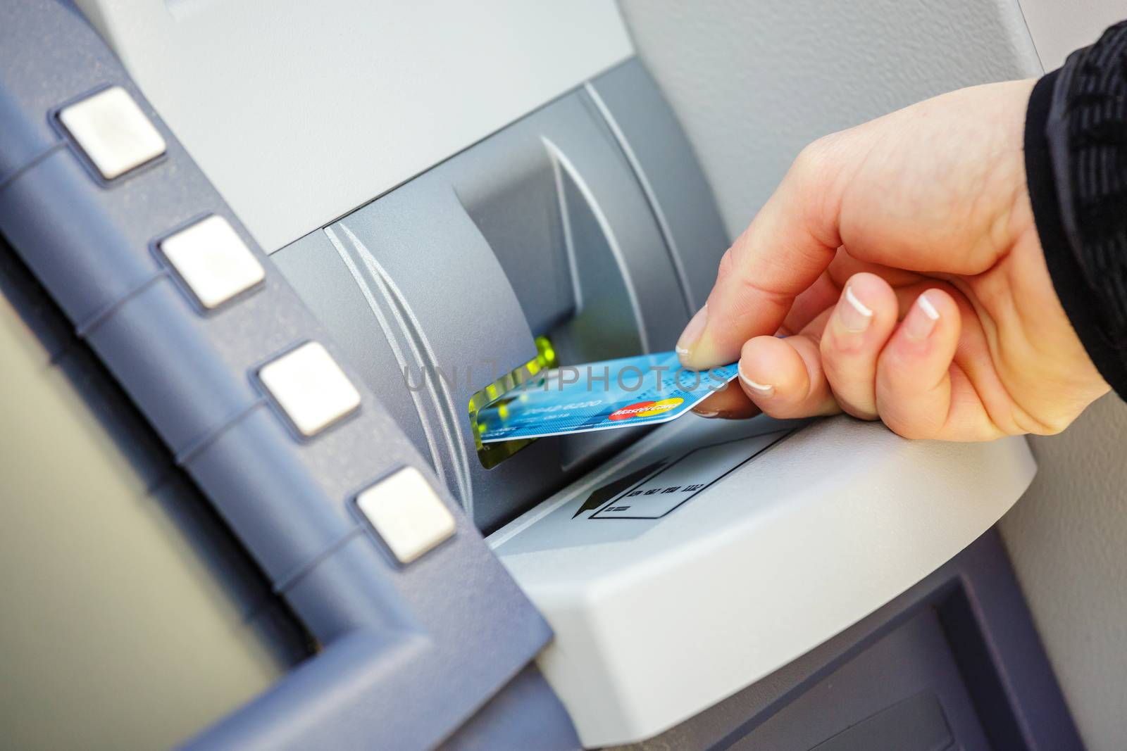 young woman inserting a credit card to ATM by pixinoo