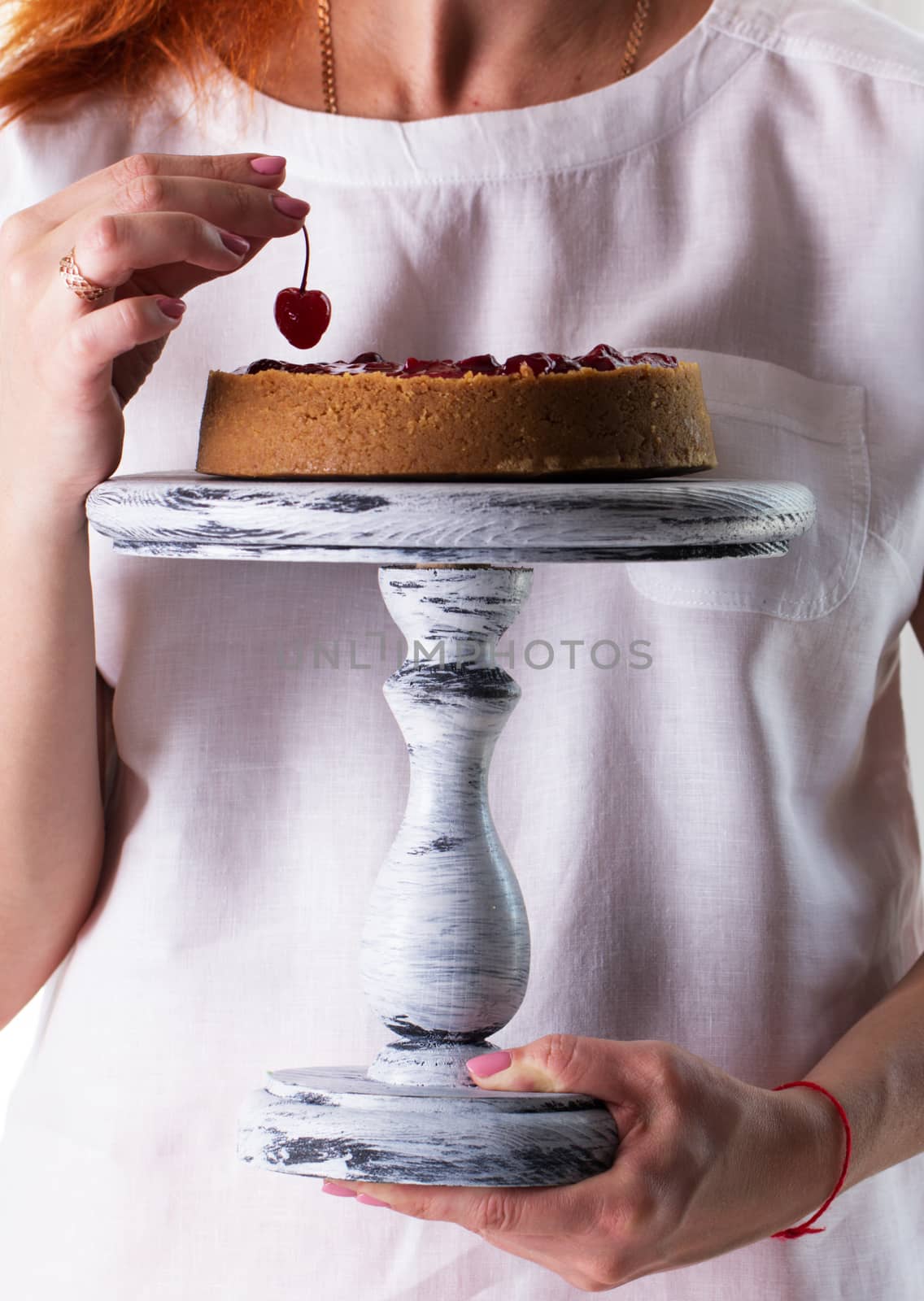 Woman's hands hold a  cheesecake on a wooden cake stand by kate_ovcharenko