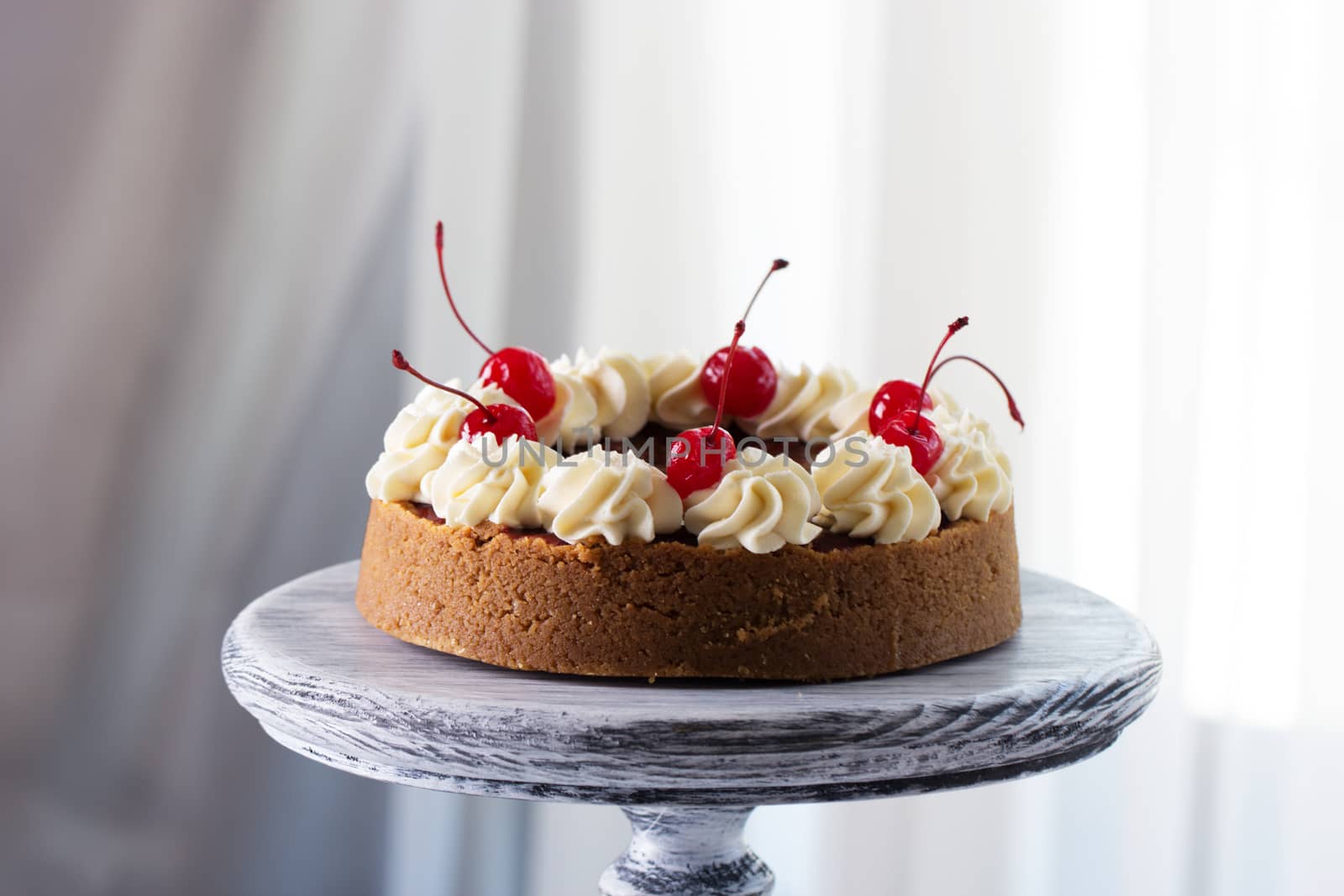 Cheesecake decorated with cherry sauce with berries on a wooden cake stand
