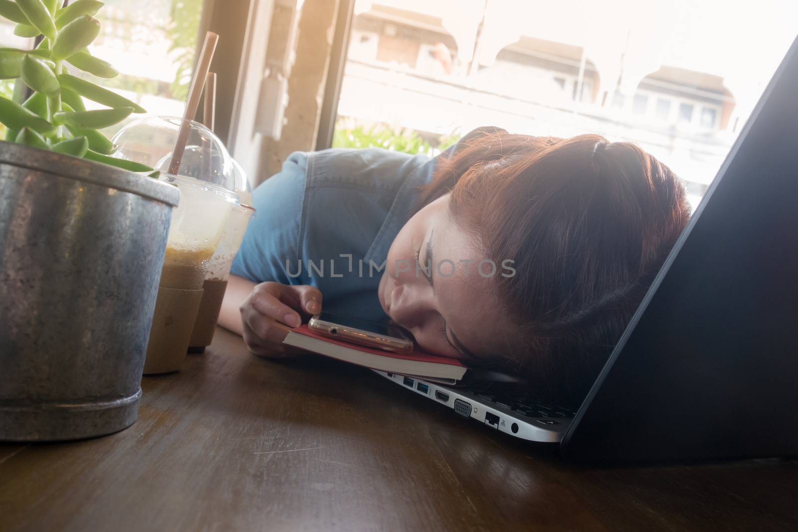 Young Hipster woman sleeping while working working with laptop computer in coffee shop. exhausted worker on busy day. Freelance business activity concept.