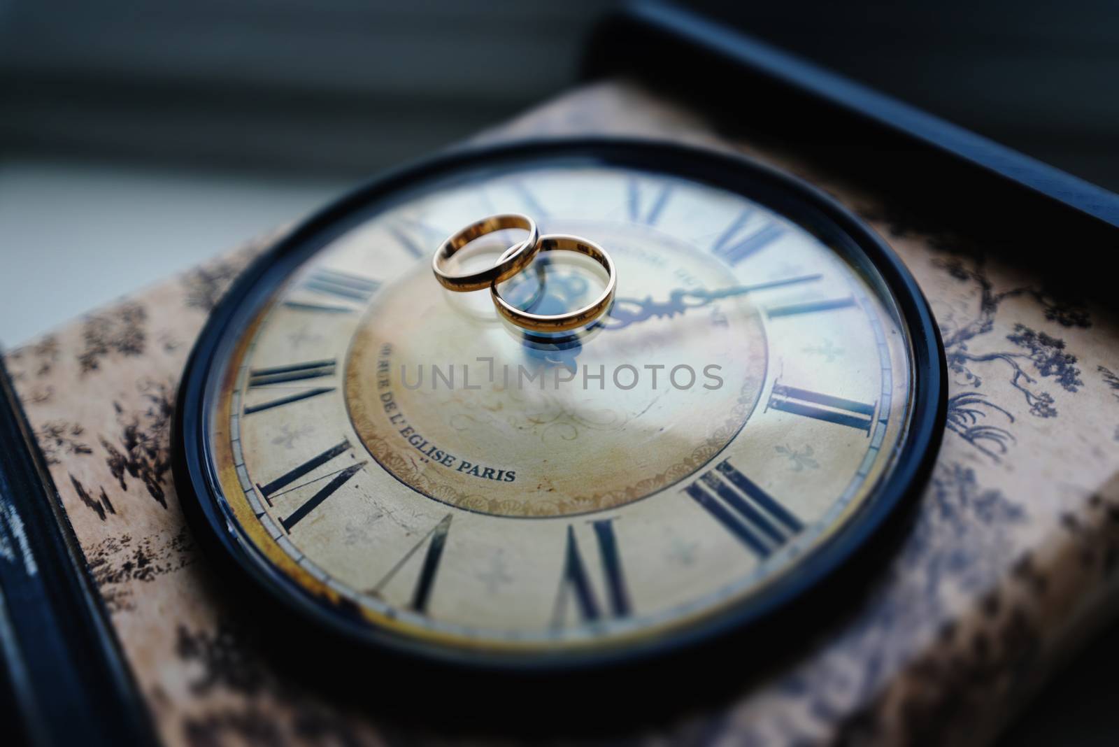 Gold wedding rings lie on the clock