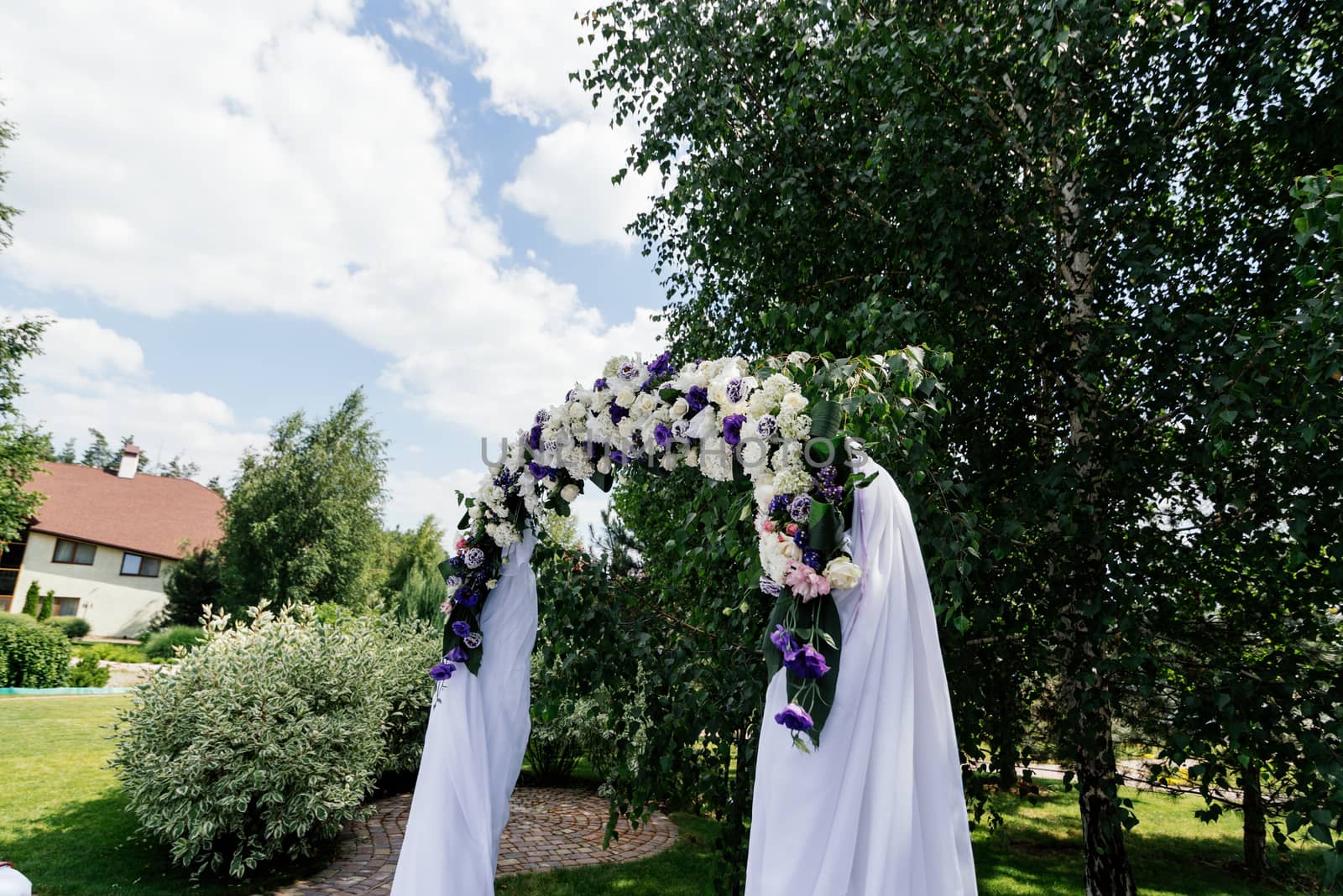Wedding arch with flowers and white cloth near the birch