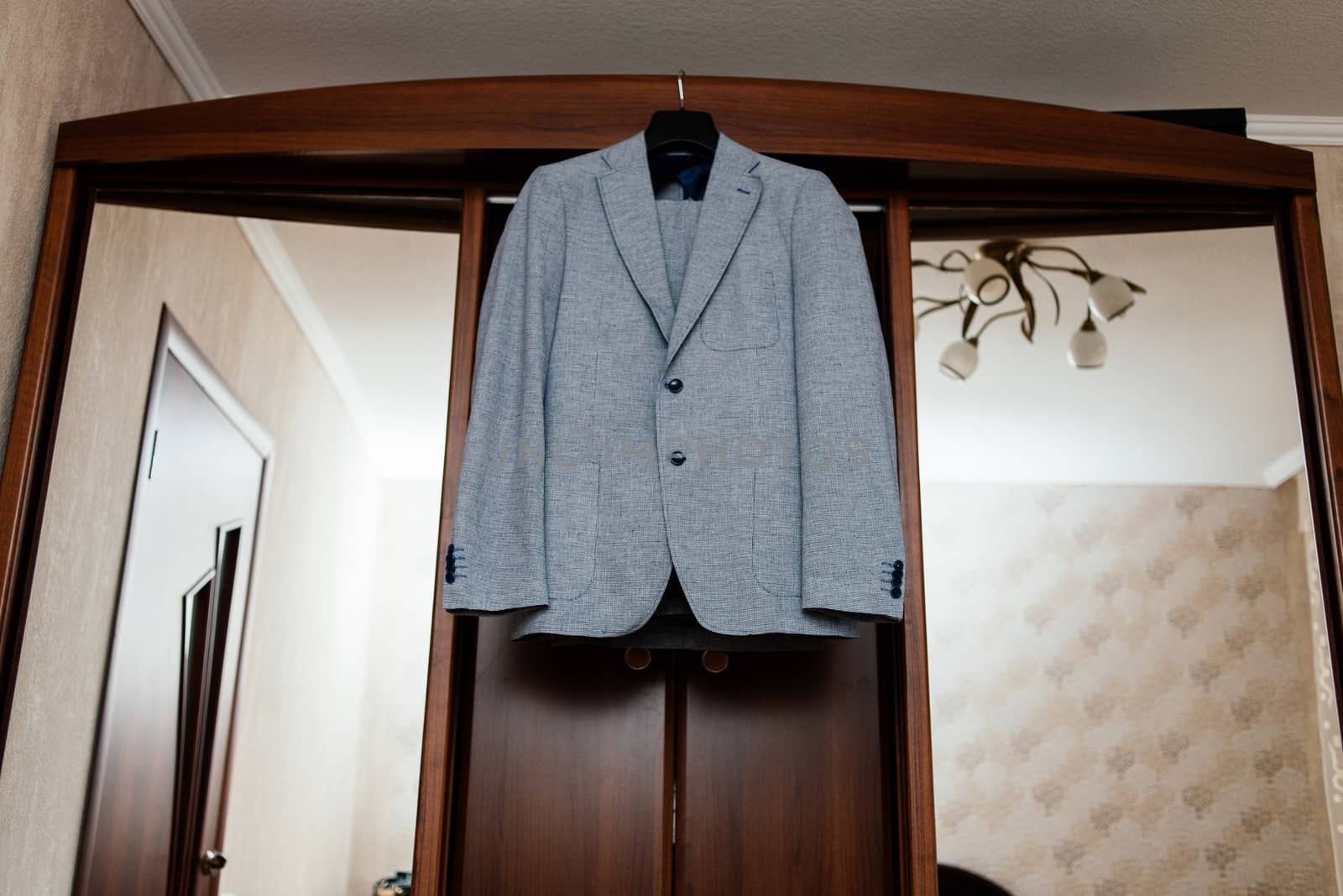 Beautiful gray groom's suit hanging on the wardrobe in the room