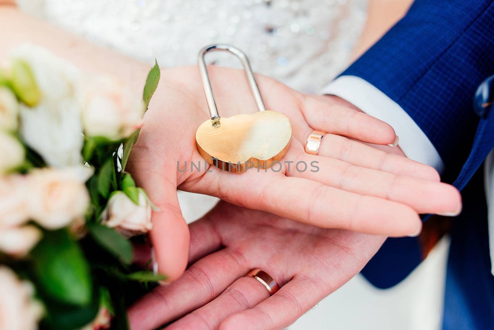 Gold wedding lock in the form of heart in the hands of the bride and groom. 