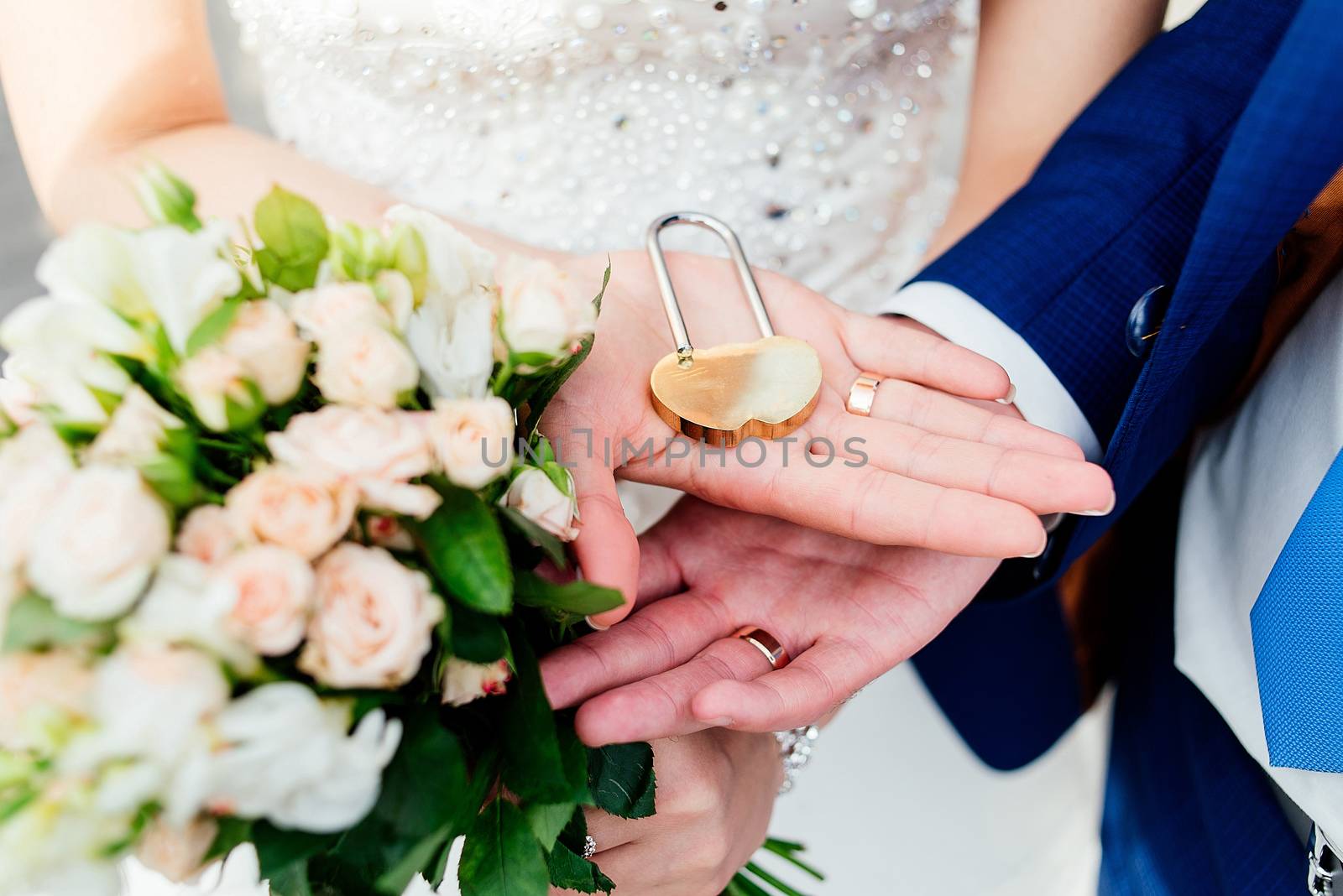 Gold wedding lock in the form of heart in the hands of the bride and groom. 