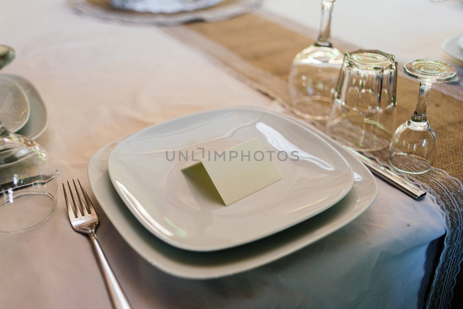 Blank card for guests on a white empty plate on a dinner table