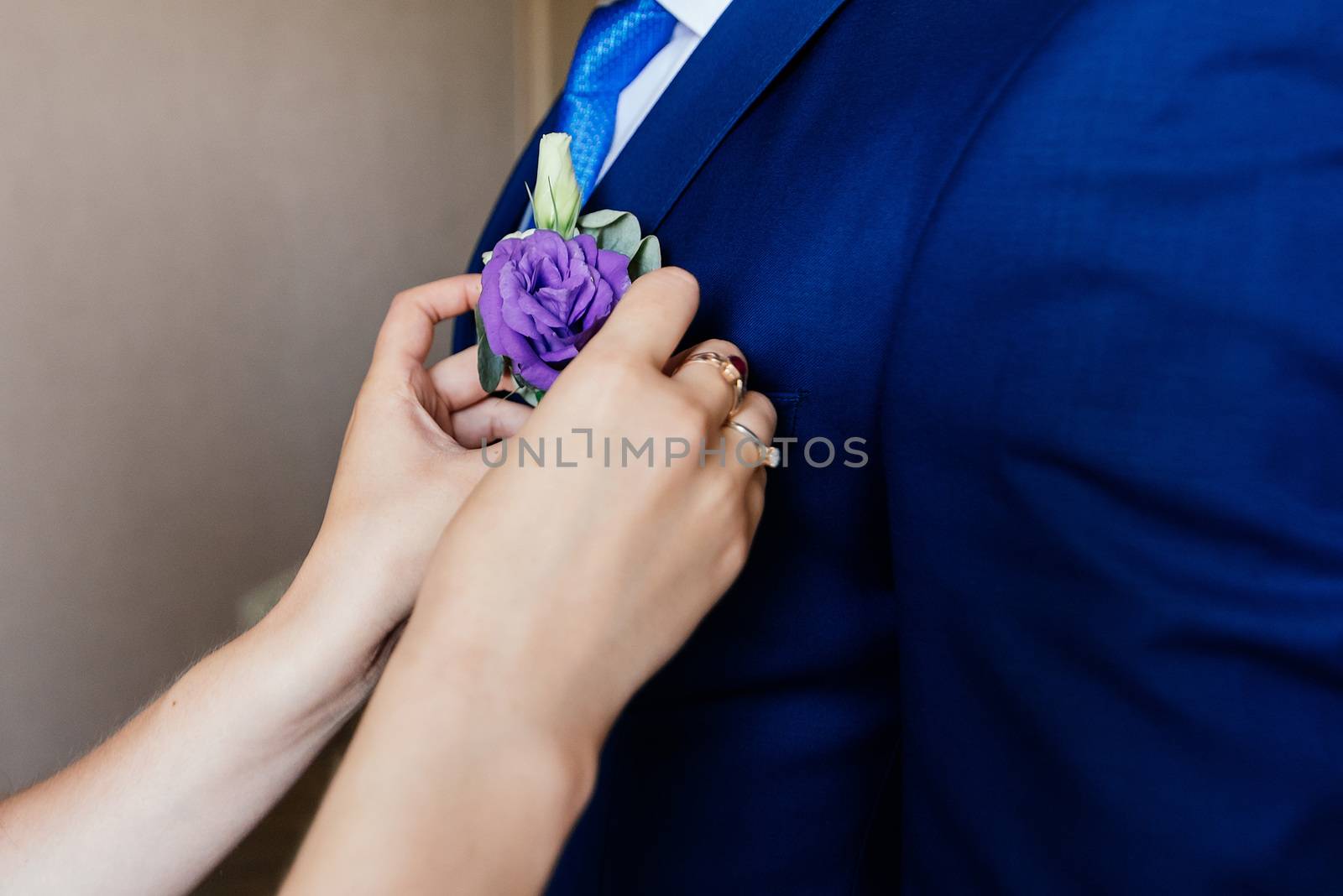 Woman inserting the boutonniere in buttonhole of man in suit