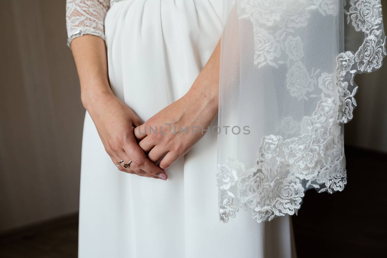 Bride's hands crossed on white dress