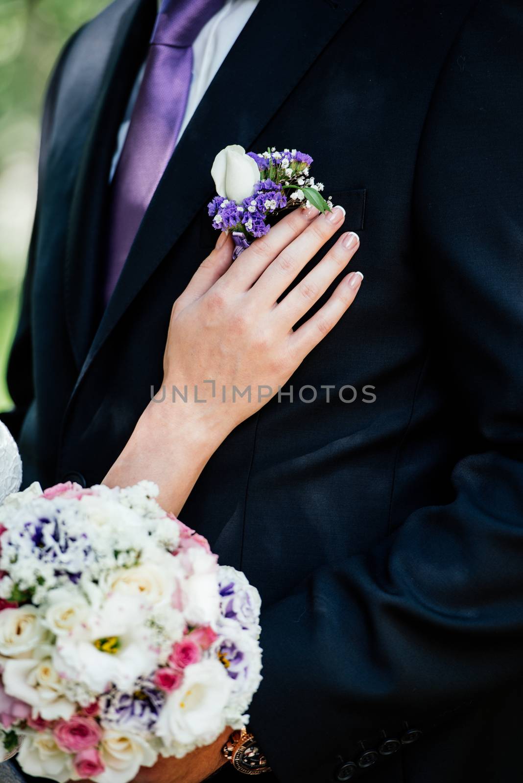 Woman inserting the boutonniere in buttonhole of man in suit