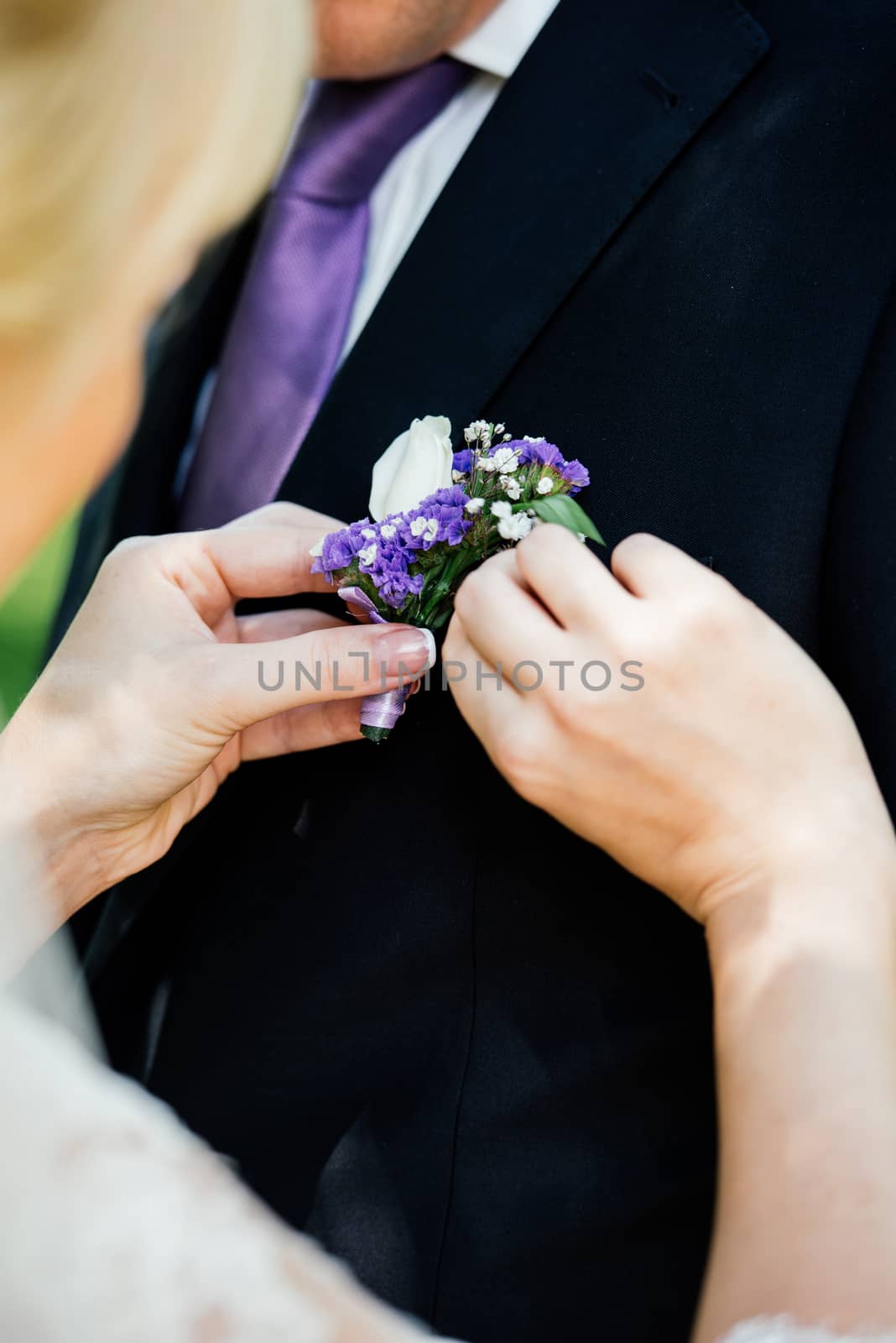 Woman inserting the boutonniere in buttonhole of man in suit