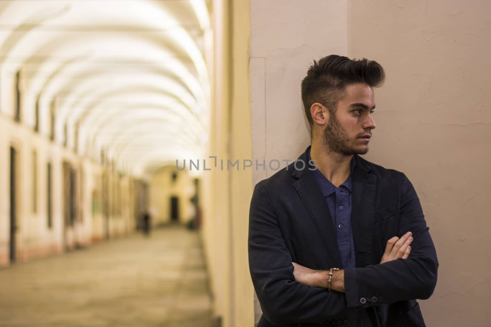 Handsome young man under cloisters in Italian city at night by artofphoto