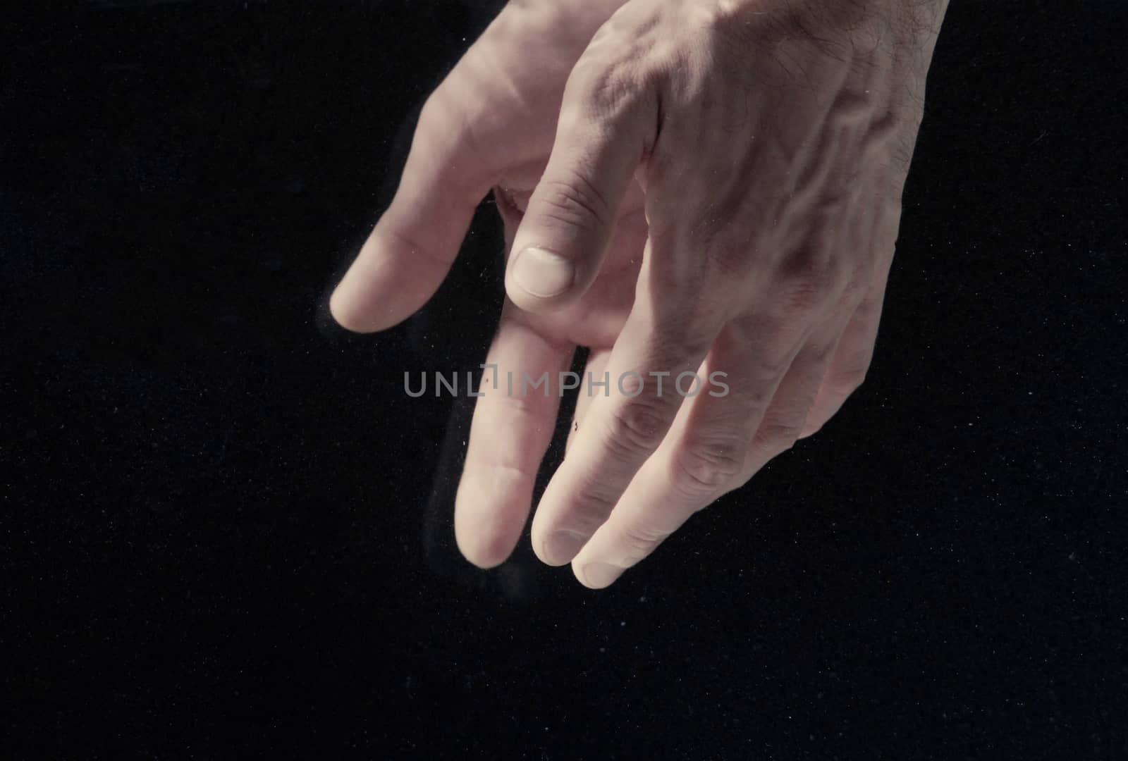 Man's hands under water on black background