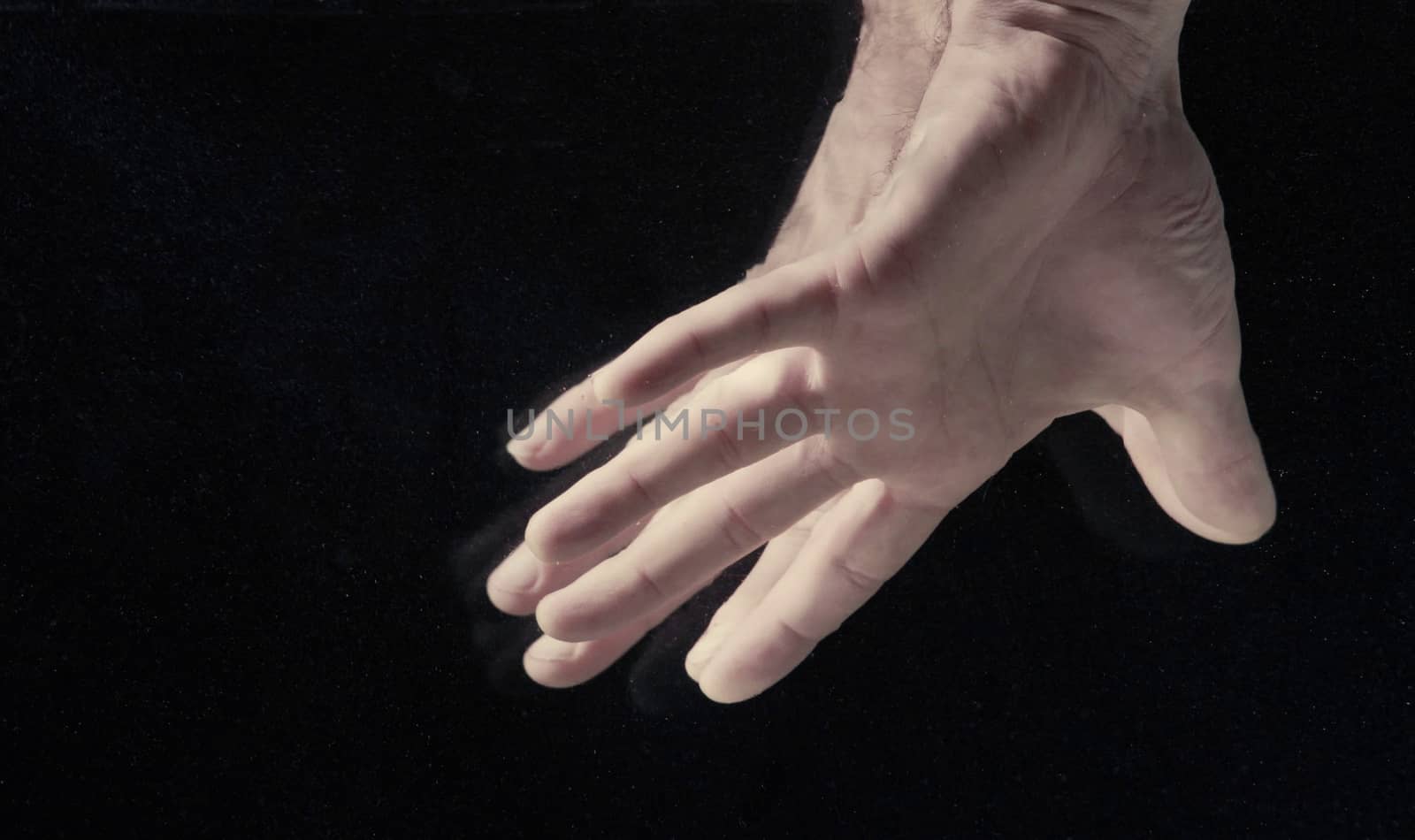 Man's hands under water on black background