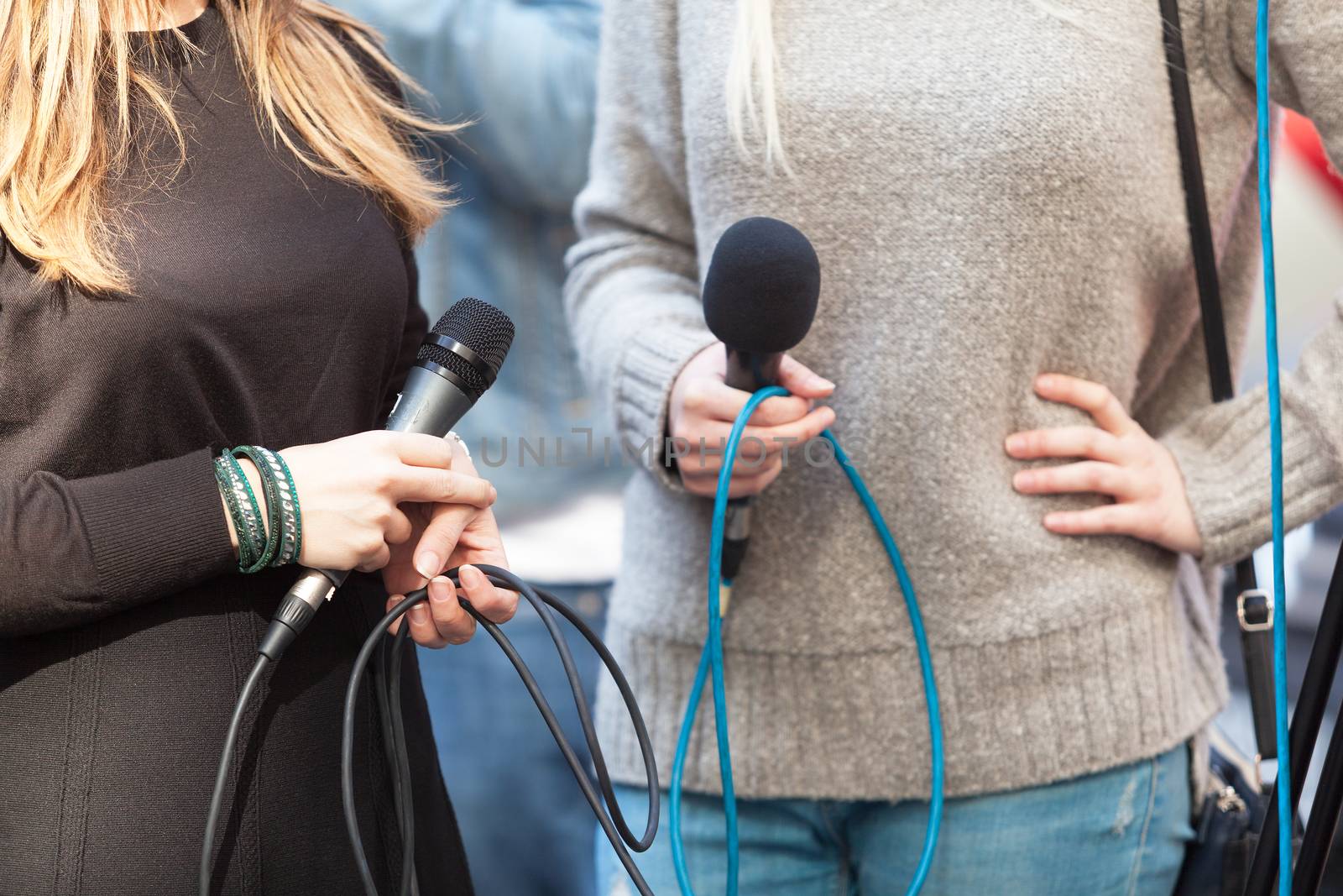 Female reporters holding microphones waiting for news conference by wellphoto