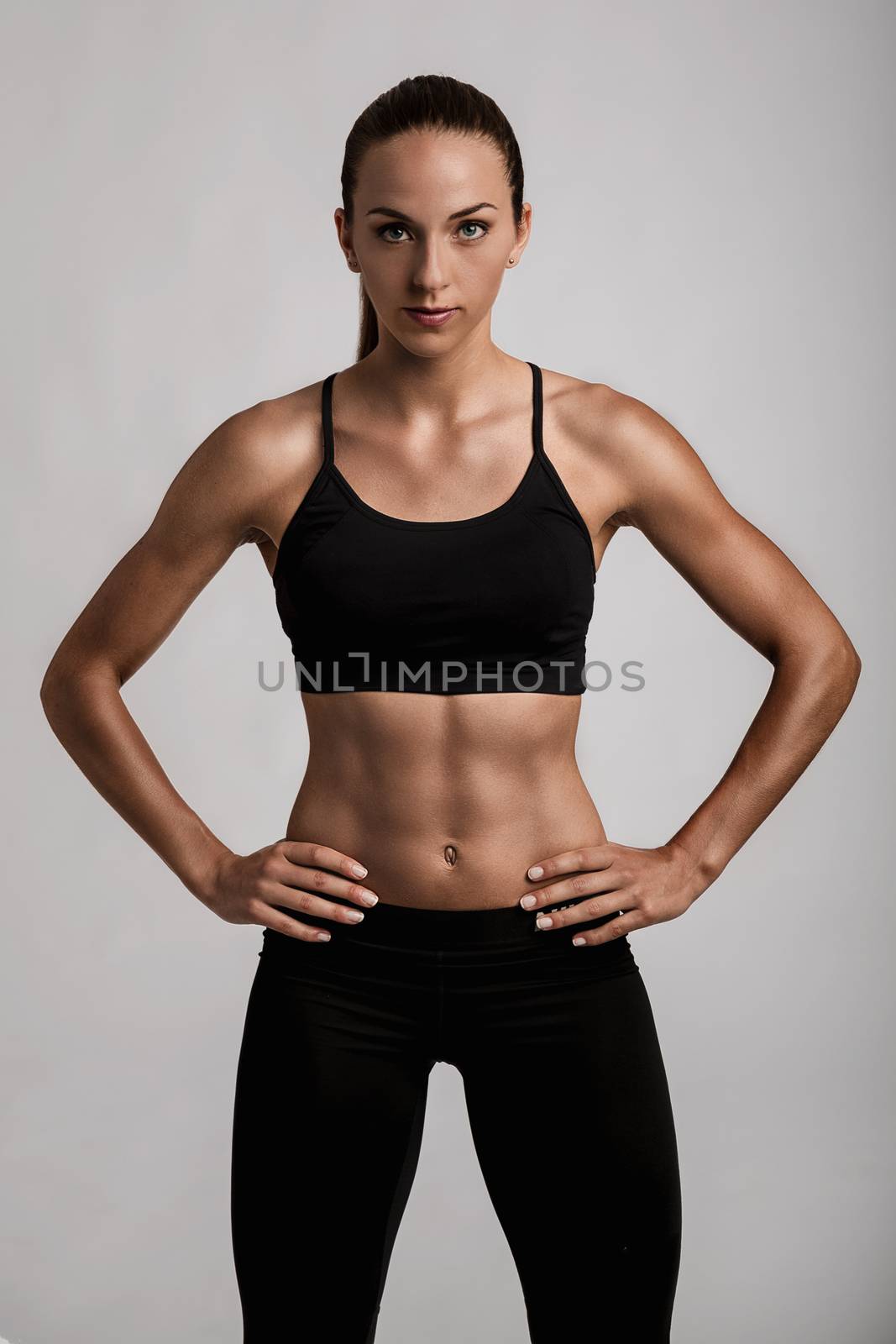Portrait of sporty young woman with muscular body looking at camera