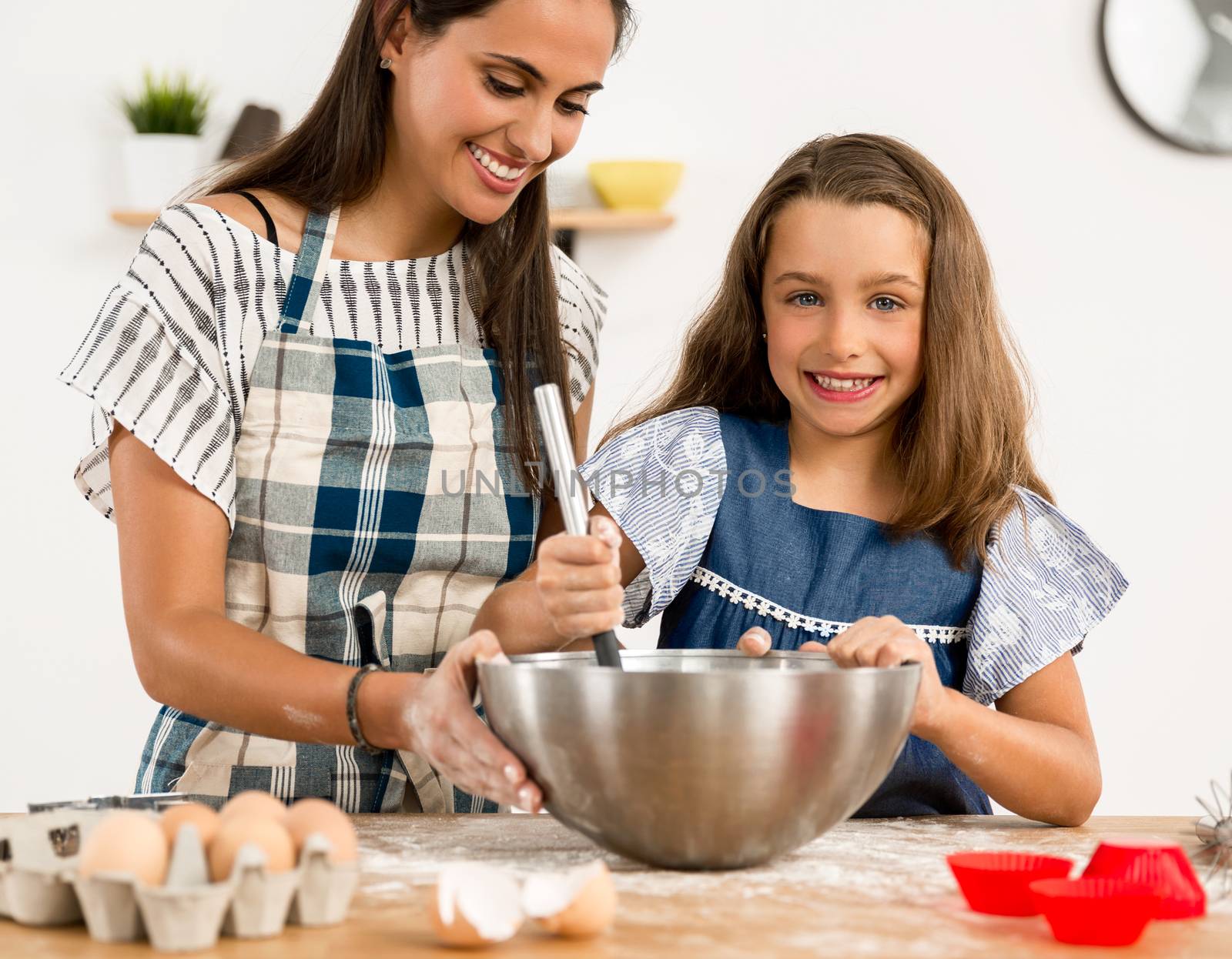 Shot of a mother and daughter having fun in the kitchen and learning to make a cake