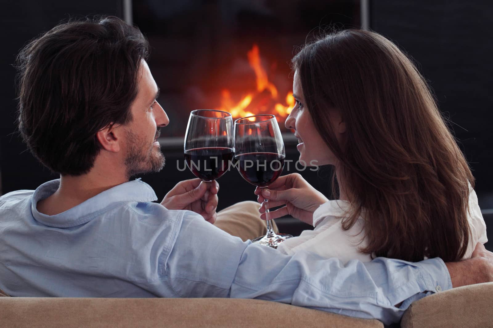 Romantic couple drinking wine at home near fireplace