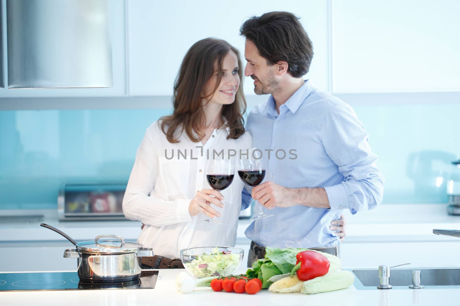 Portrait of a couple having a glass of red wine while cooking dinner